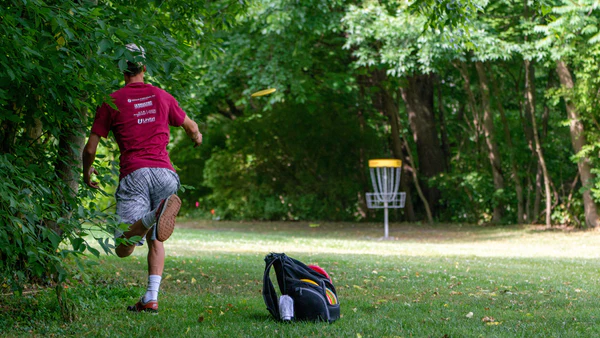 joueur-de-disc-golf-lance-frisbee-jaune-dans-le-panier-frisbee-ultimate