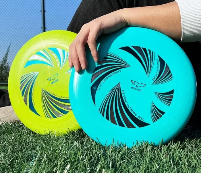 Frisbee Ultimate Yikun - Série UltiPro Ultiwave Disc - Vert et Bleu Ciel posés sur l'herbe